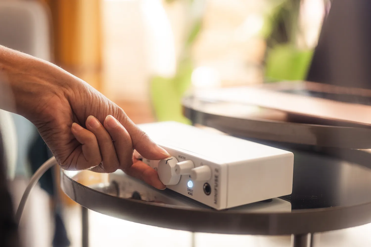 Lifestyle Arturia Recording minifuse Pack White. Se ve una mano manipulando la interfaz de audio