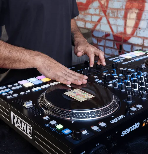 Vista de cerca del controlador DJ Rane Performer destacando la rueda de control con pantalla integrada y controles iluminados. La pantalla de la rueda muestra formas de onda y datos de la pista, proporcionando información esencial para el DJ.